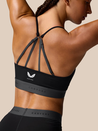 Back view of the black Adapt Training Sports Bra with slender cross straps and Castore logo band along the bottom.