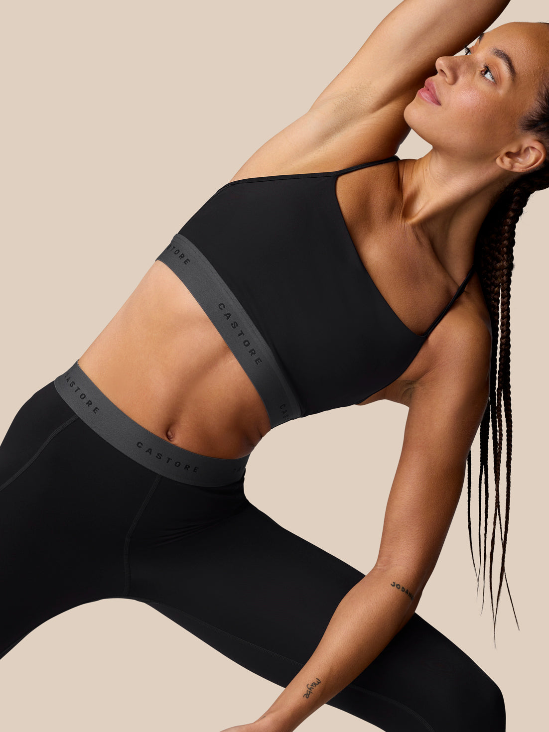 Side back shot of the Adapt Training Sports Bra in black showing an open back with multiple straps and Castore logo band.