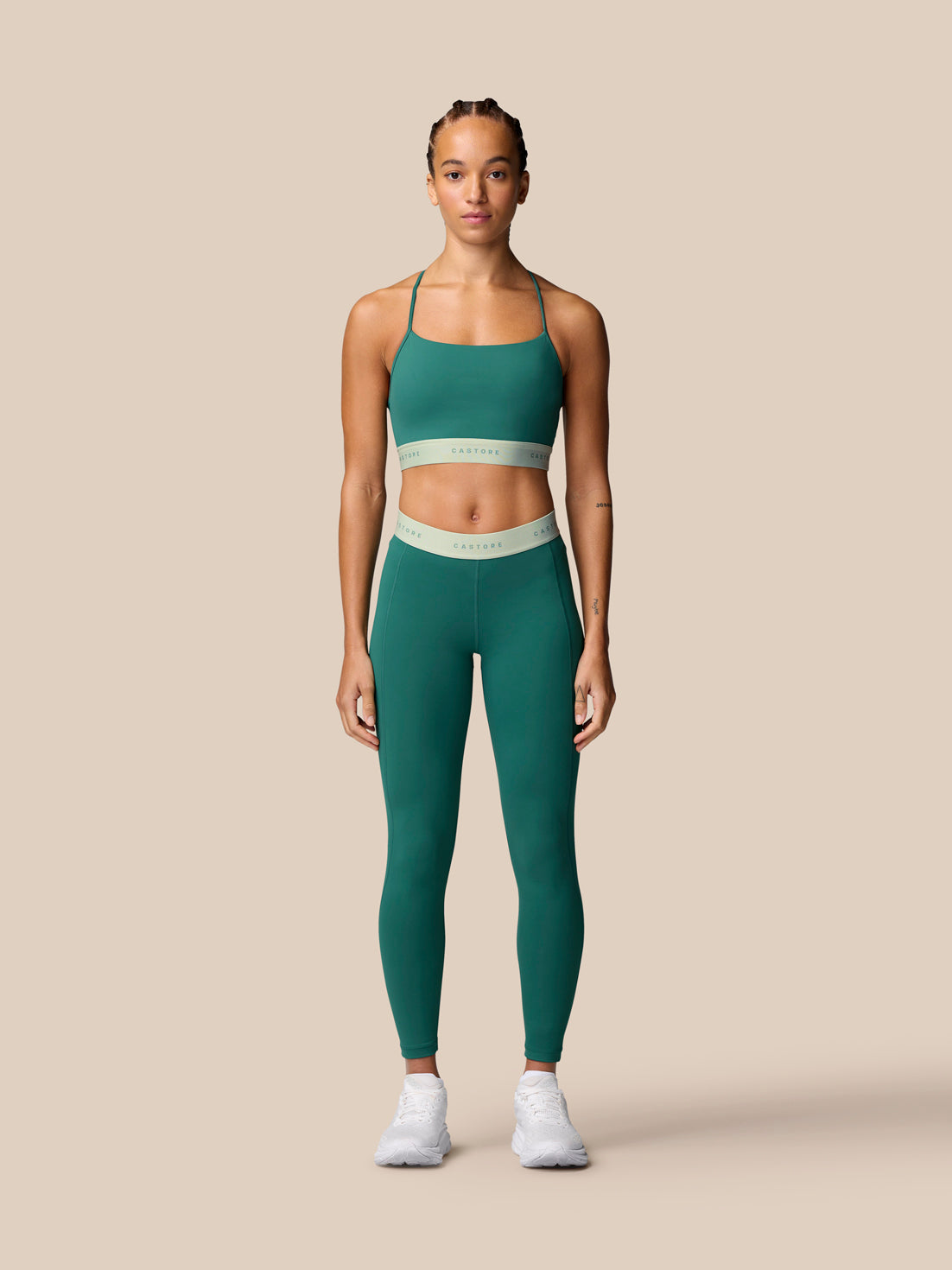 Front view of model wearing seafoam Adapt Training Sports Bra with matching leggings against a beige background.