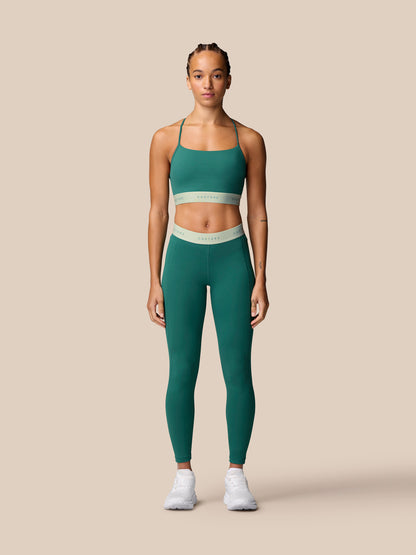 Front view of model wearing seafoam Adapt Training Sports Bra with matching leggings against a beige background.