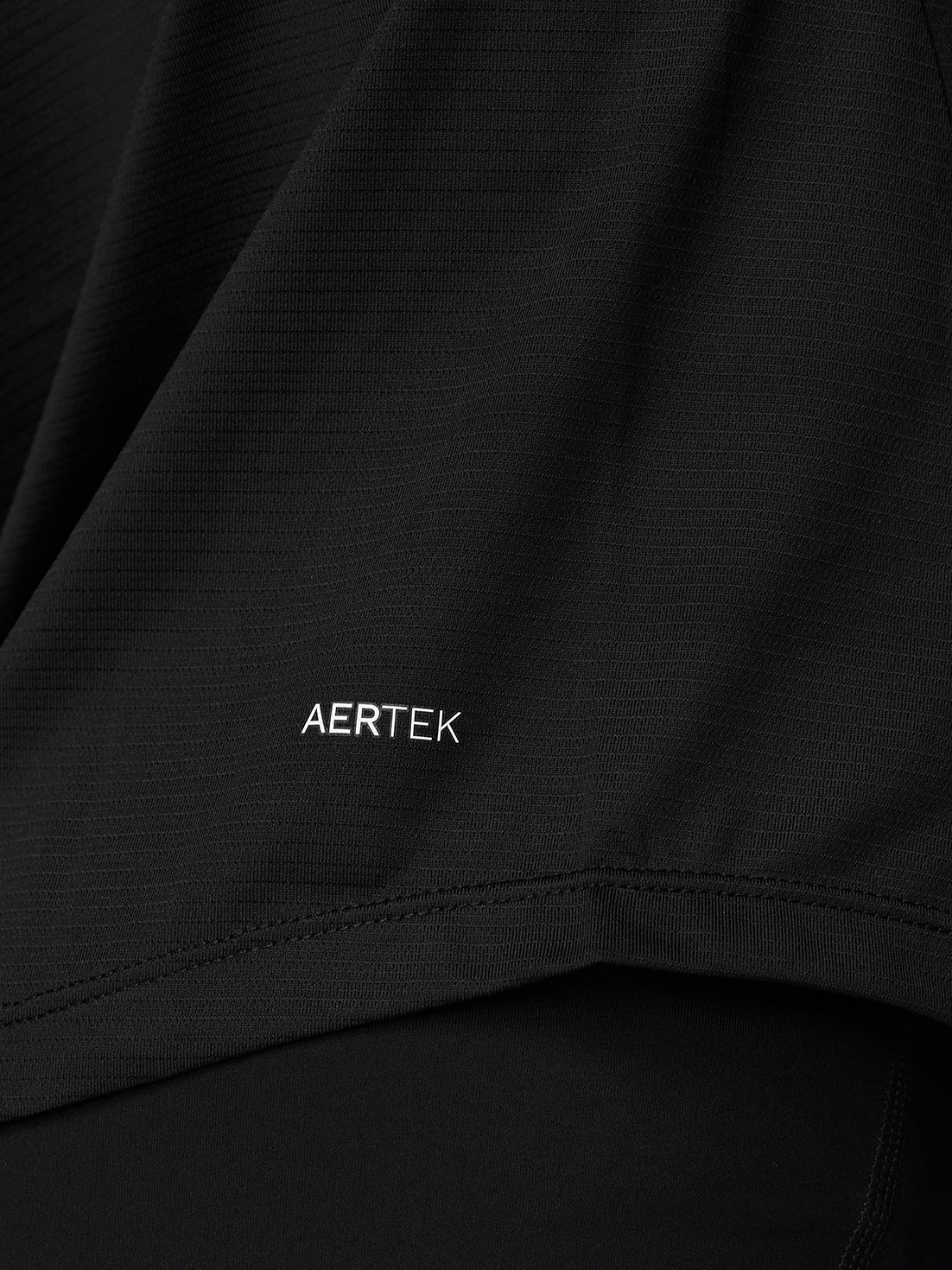 Close up of black fabric with AERTEK logo and subtle ribbed texture