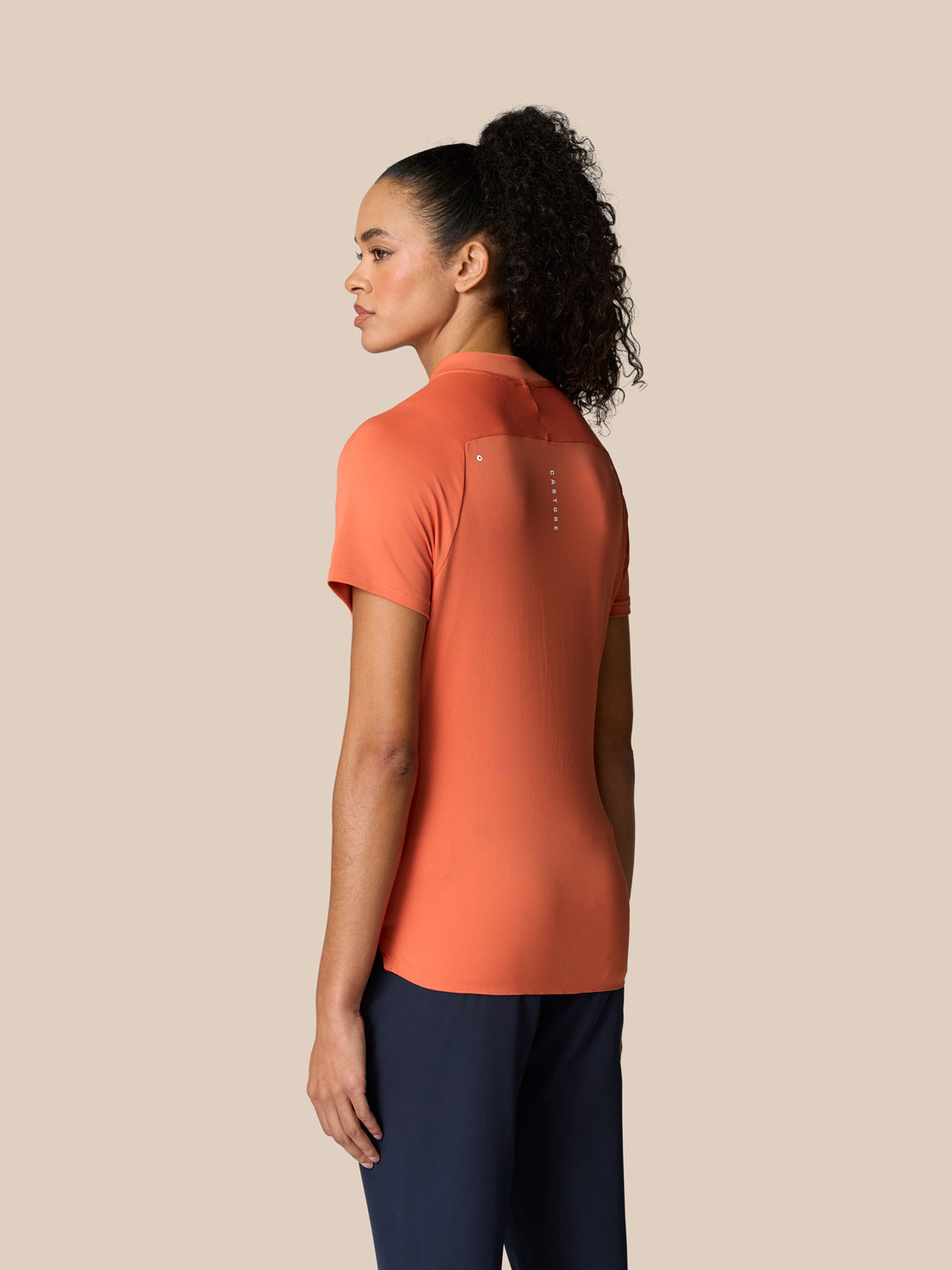 Back view of Deep Coral Pinnacle Polo on a model with a small logo along the upper back.