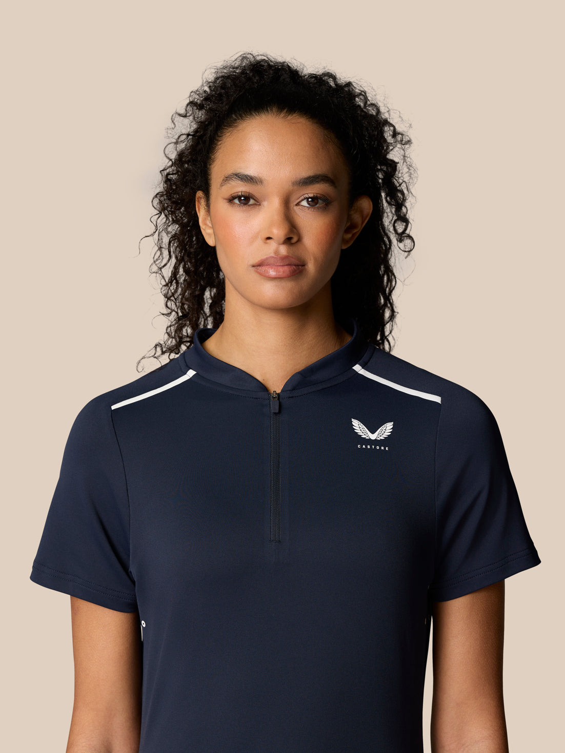 Front portrait of a woman in navy Pinnacle Polo with white shoulder piping and chest logo