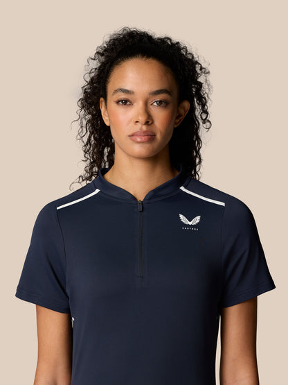 Front portrait of a woman in navy Pinnacle Polo with white shoulder piping and chest logo
