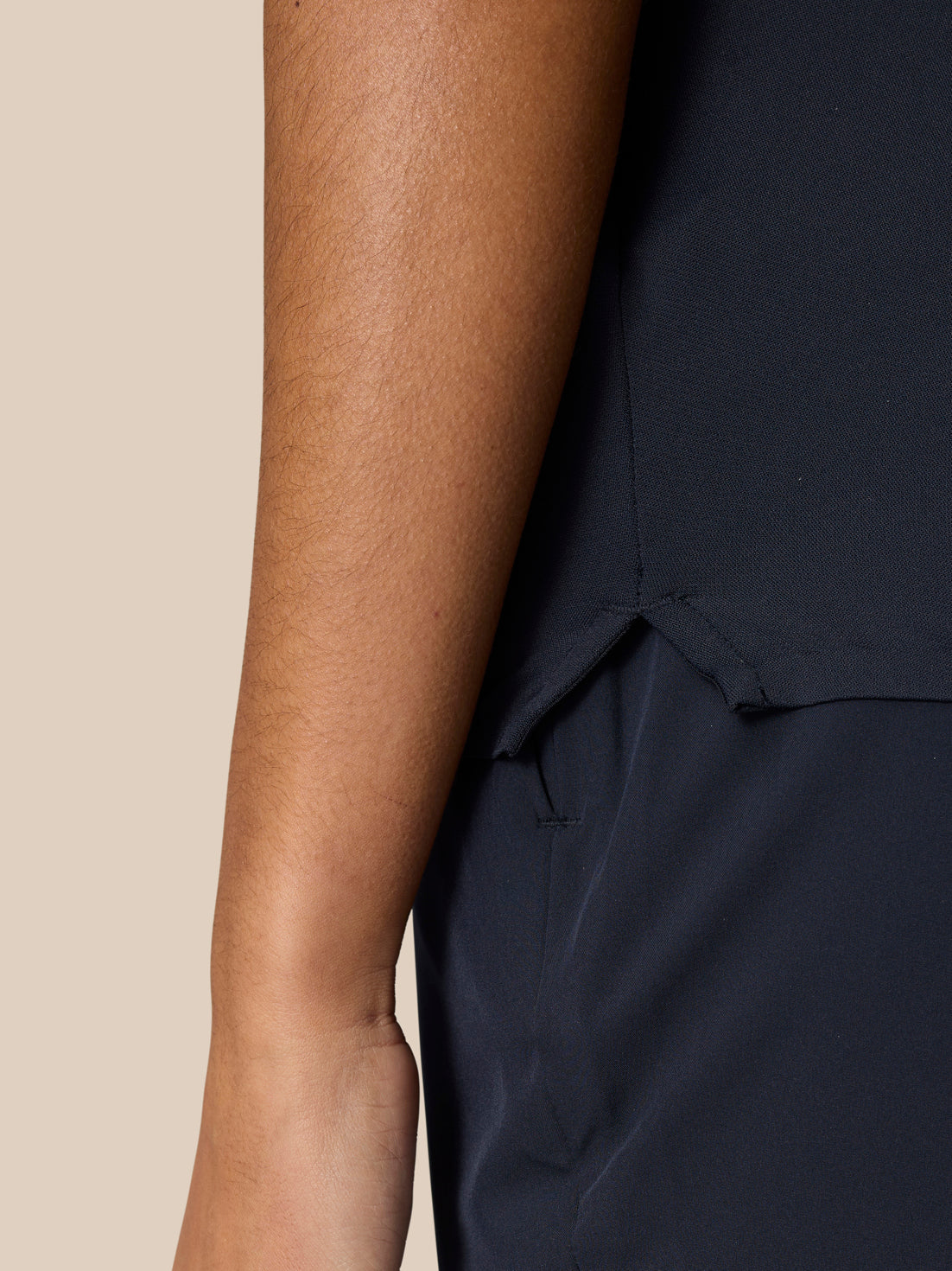 Profile view of a model in navy Pinnacle Polo highlighting underarm vent eyelets and side hem slit