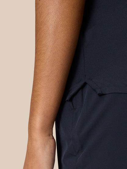 Profile view of a model in navy Pinnacle Polo highlighting underarm vent eyelets and side hem slit