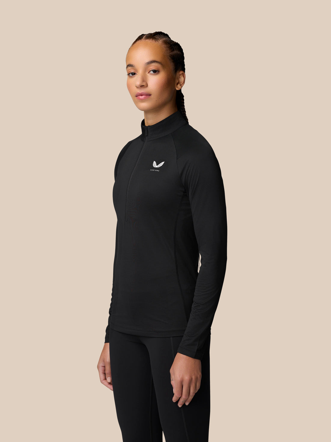 Side profile of a woman in a black Adapt Training long sleeve half zip top with a white logo on the chest.