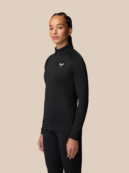 Side profile of a woman in a black Adapt Training long sleeve half zip top with a white logo on the chest.