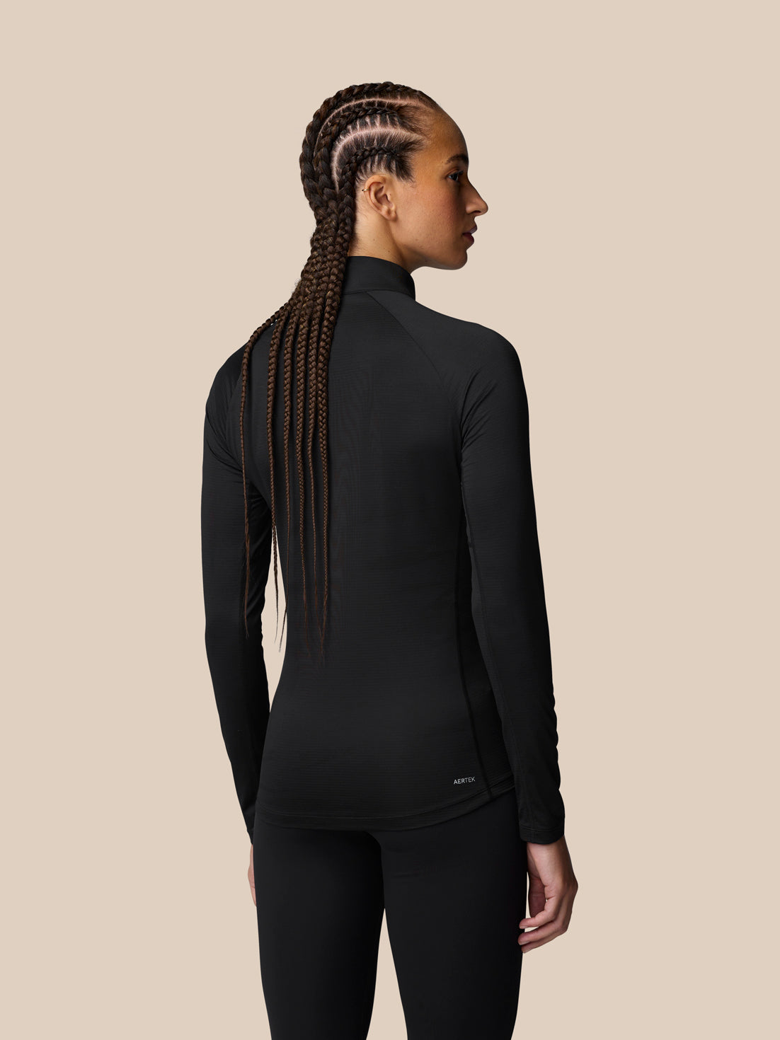 Back view of a woman wearing a black Adapt Training long sleeve top with a small logo at the lower back