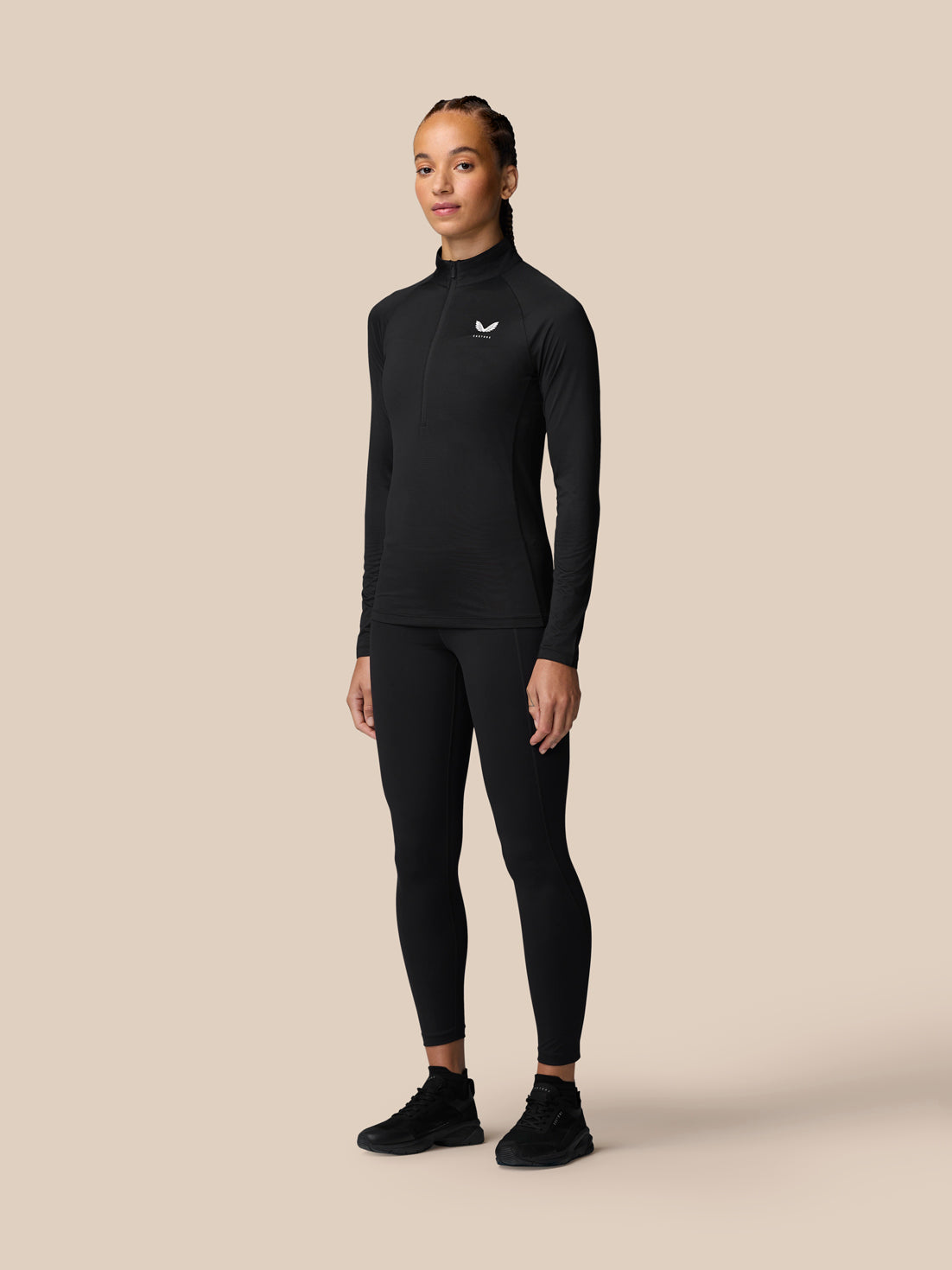 Woman wearing black Adapt Training half zip top with stand collar and small logo on left chest.