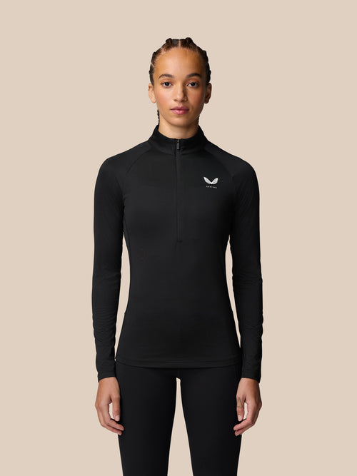 Front view of a woman wearing a black Adapt Training half zip top with a small white logo on the chest