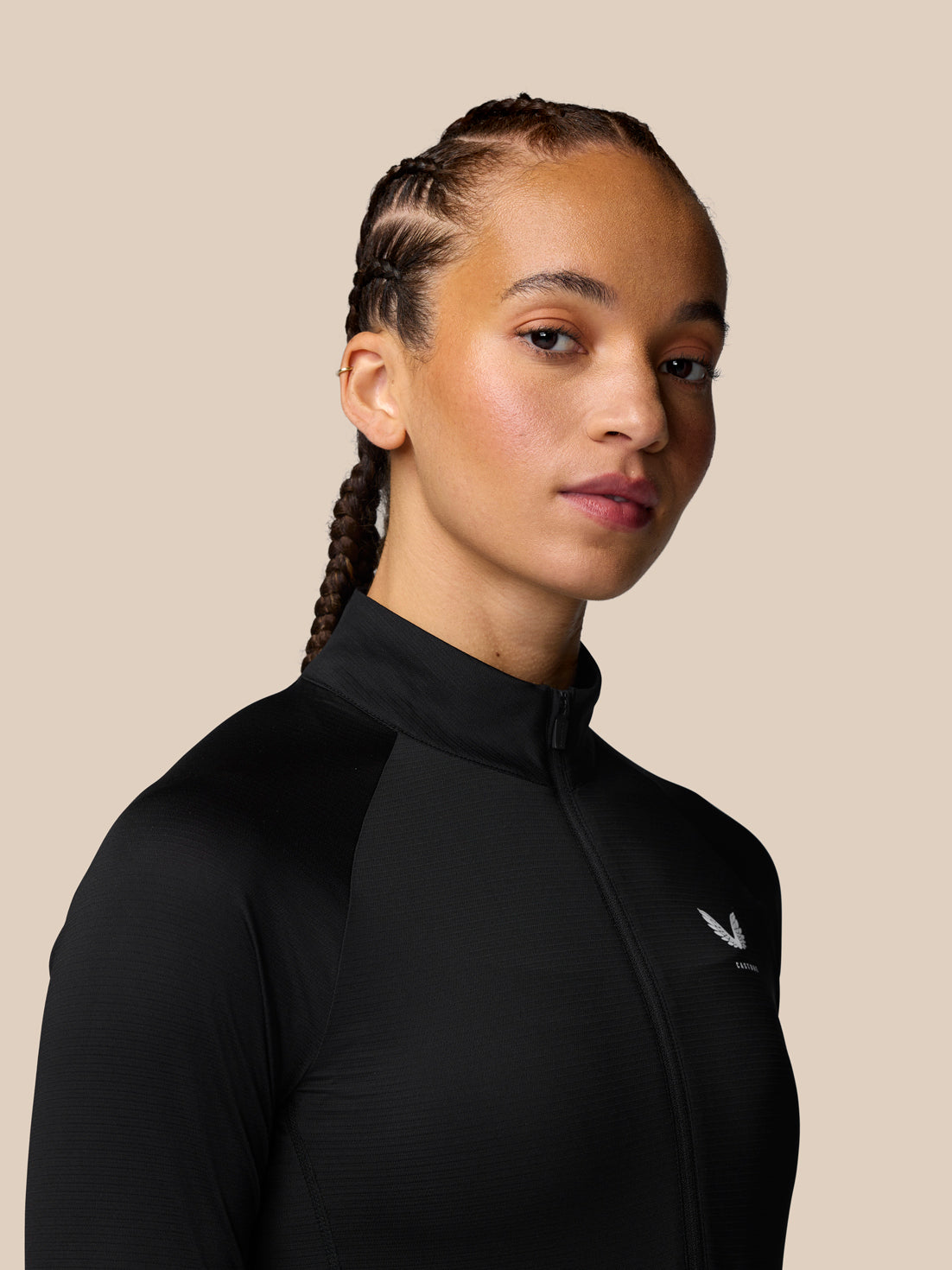 Side profile of a woman in a black Adapt Training long sleeve top with zip front and a small logo on the chest