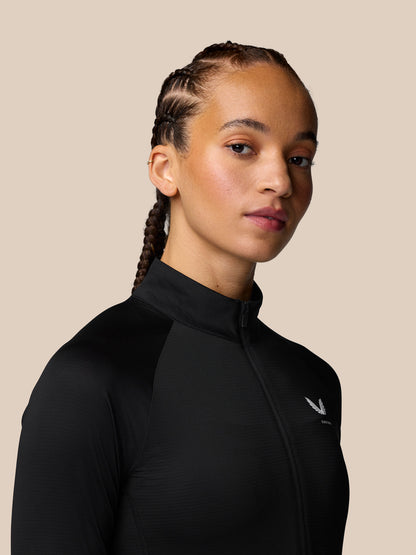 Side profile of a woman in a black Adapt Training long sleeve top with zip front and a small logo on the chest