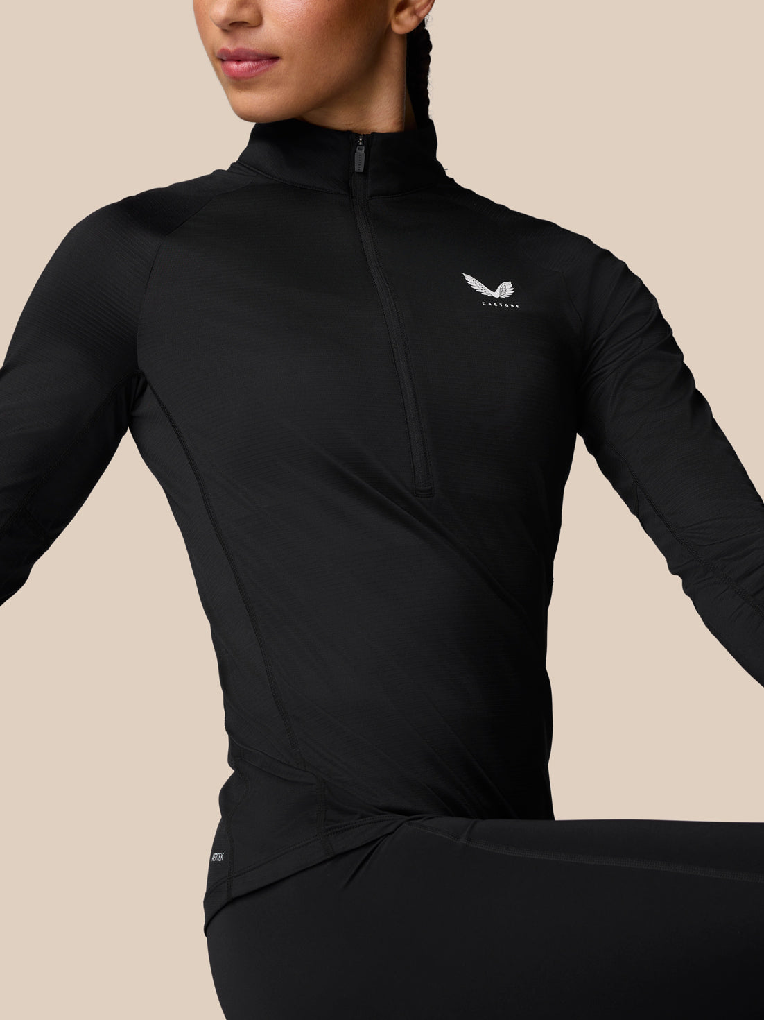 Close up of a model wearing black Adapt Training half zip top with a high collar and visible seam lines.
