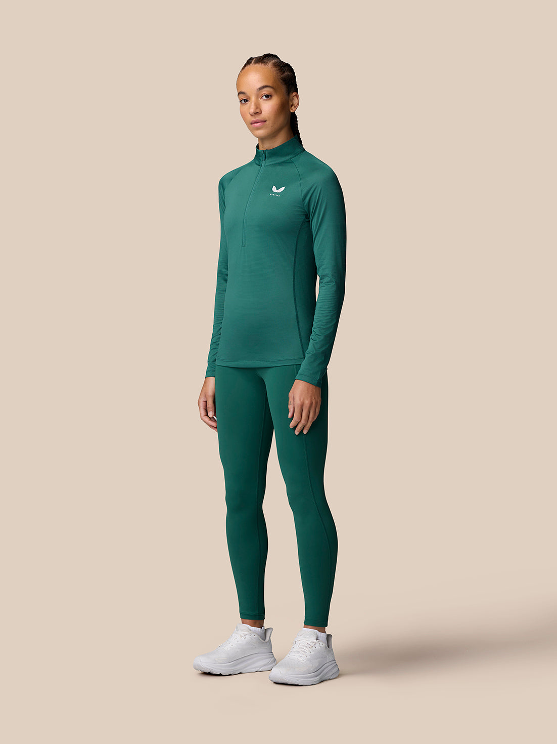 Full-body front view of a woman in seafoam Adapt Training 1/2 Zip Top with matching leggings and white sneakers