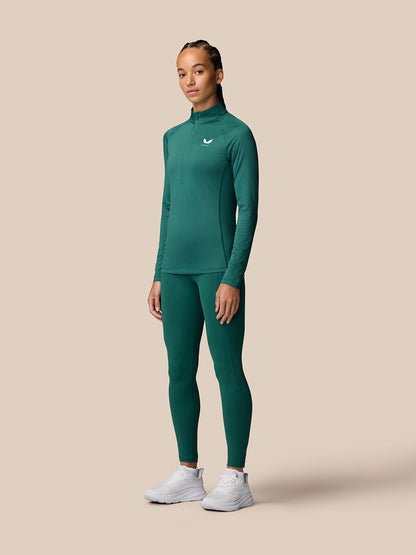 Full-body front view of a woman in seafoam Adapt Training 1/2 Zip Top with matching leggings and white sneakers