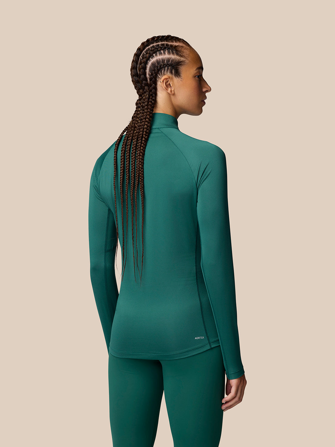 Back view of a woman wearing seafoam Adapt Training long sleeve top with braided hair