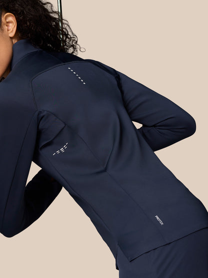 Angled back view of model wearing Midnight Navy Pinnacle LVS ½ Zip Top highlighting sleek silhouette and logo details.