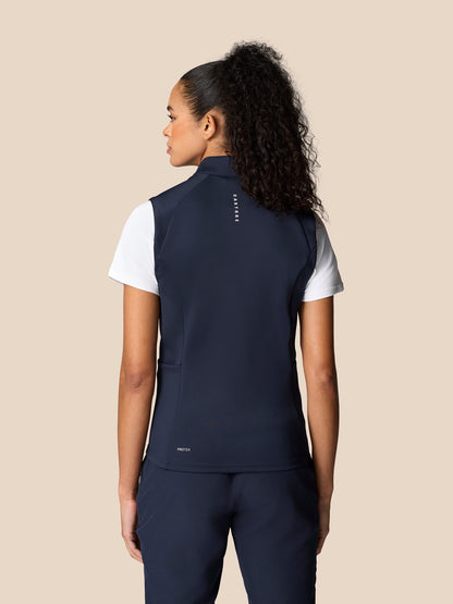 Back view of model wearing navy Pinnacle Hybrid Gilet over white T shirt, reflective branding on upper back