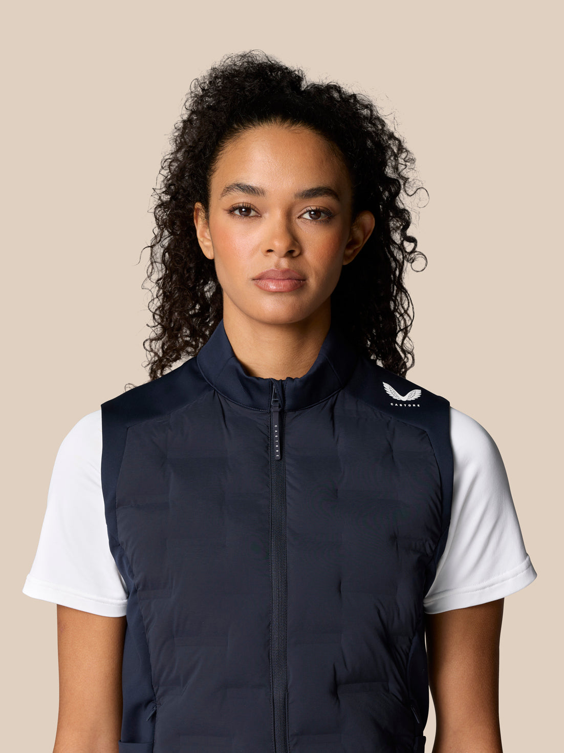 Front view of a woman wearing a navy Pinnacle Hybrid Gilet over a white T shirt