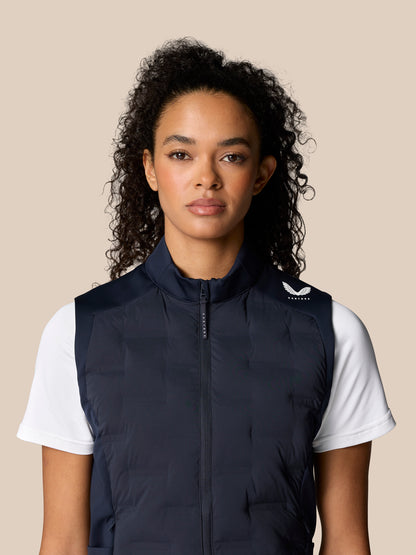 Front view of a woman wearing a navy Pinnacle Hybrid Gilet over a white T shirt