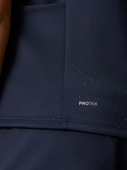 Close-up of navy Pinnacle Hybrid Gilet fabric showing PROTEK branding and scattered water droplets