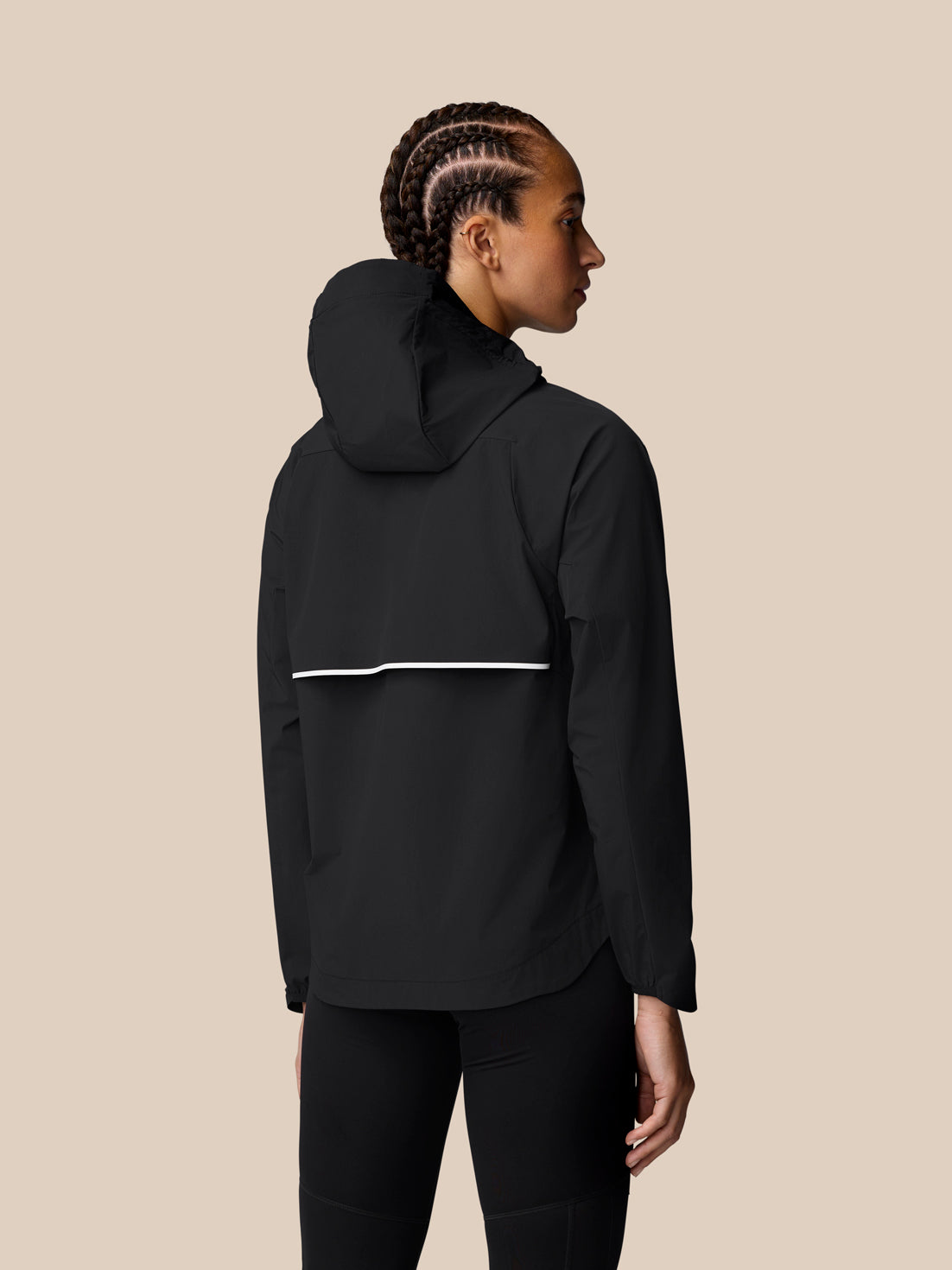 Back view of a black Apex Wind Jacket with hood and a white reflective band across the back