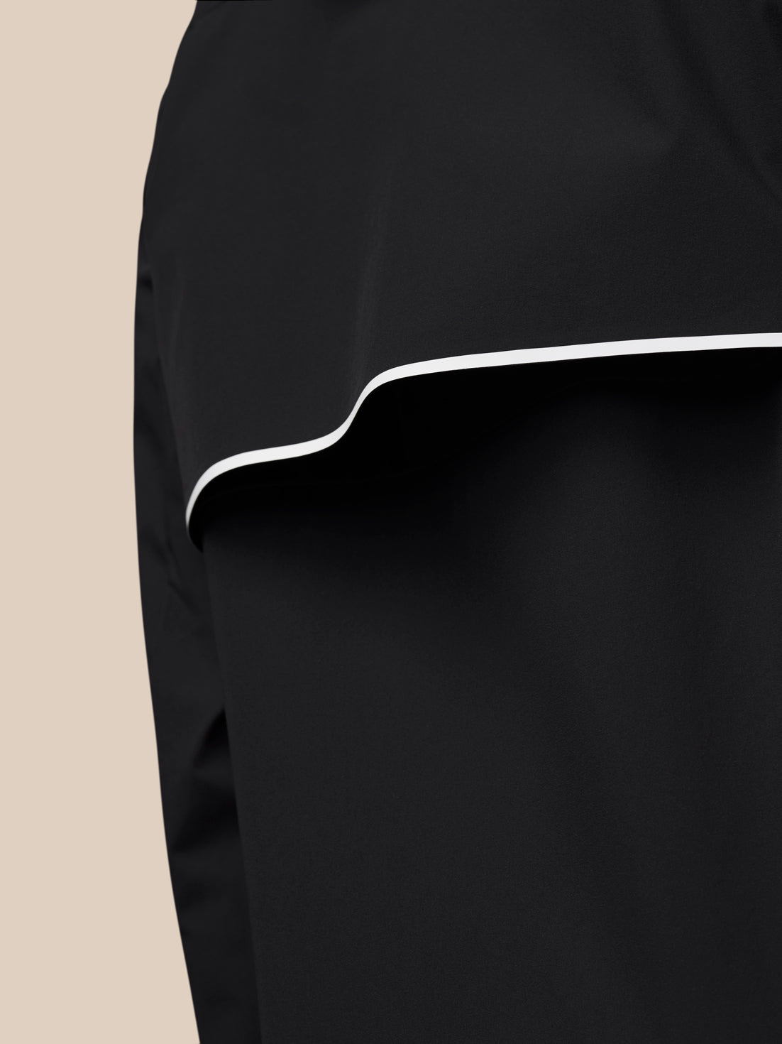 Close-up of the black wind jacket hem with white piping detail