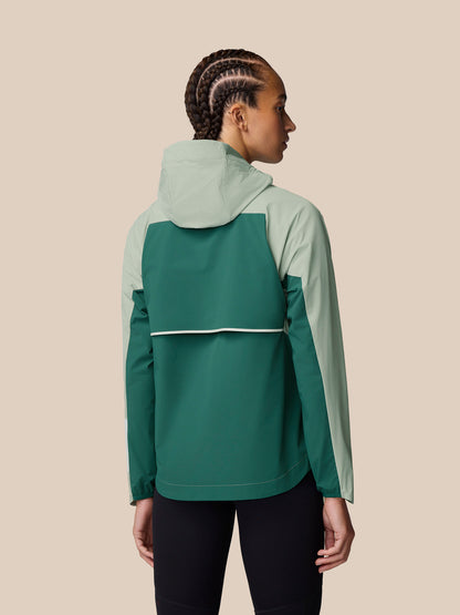 Back view of Sage Apex Wind Jacket showing color block design with light sage and dark green panels and hood