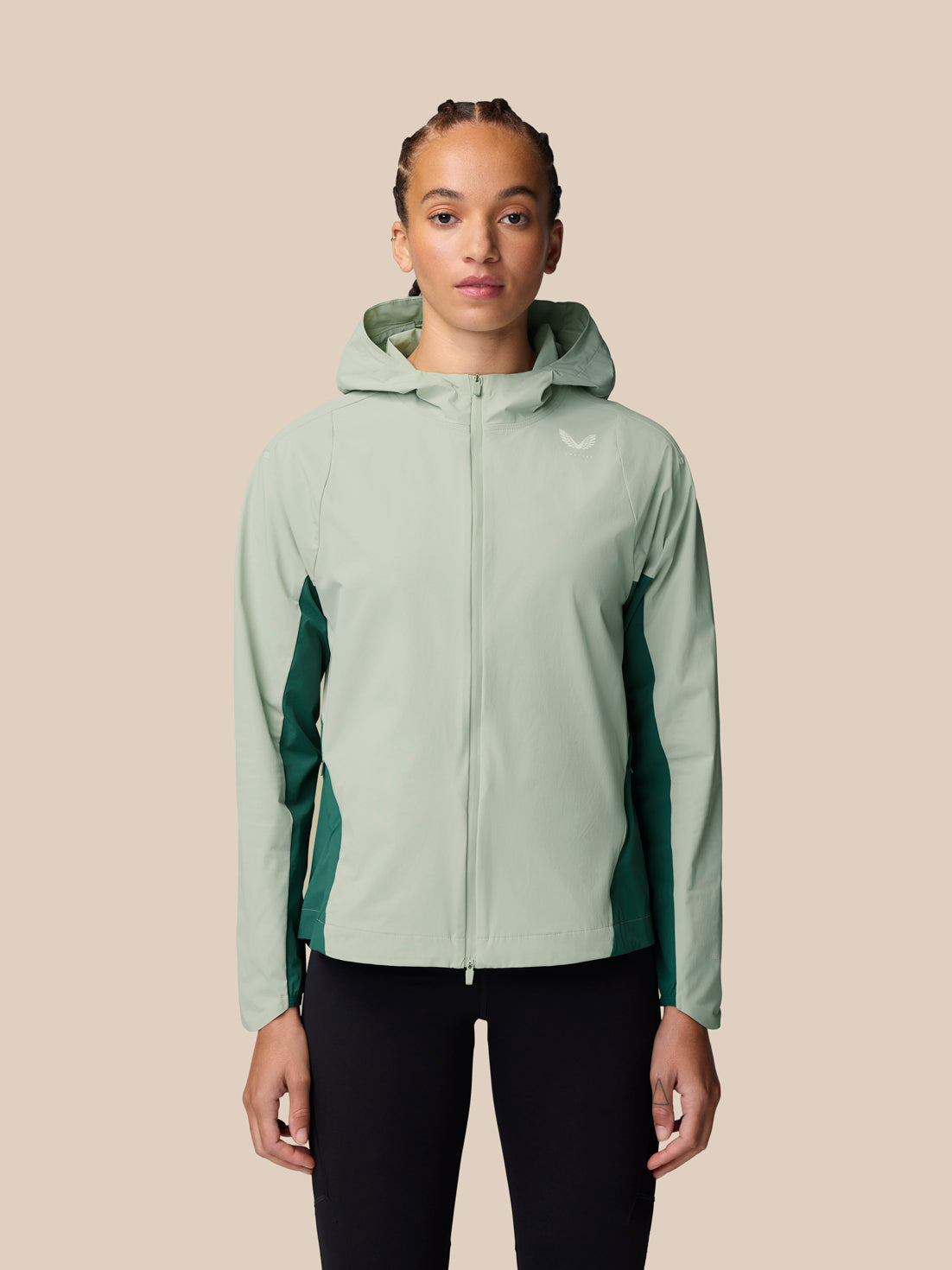 Model wearing Sage Apex Training Wind Jacket with hood, light sage body and dark green side panels