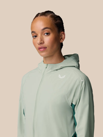 Female model wearing Sage Apex Training Wind Jacket with hood, light mint color and chest logo.