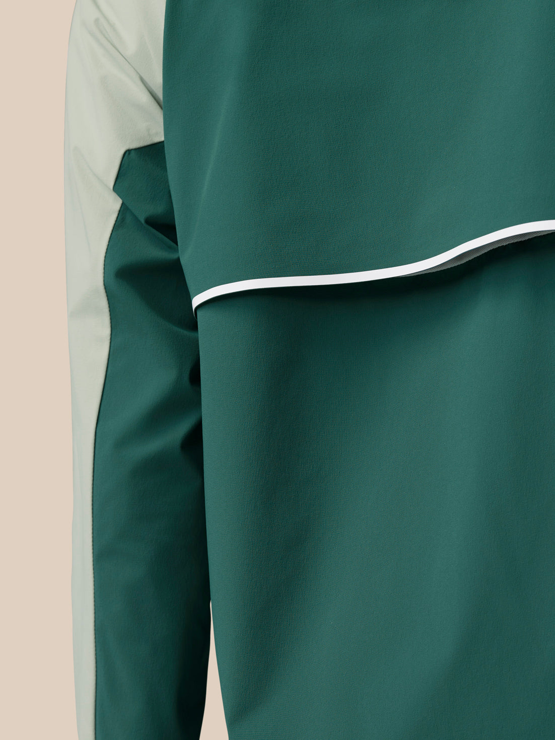 Close up of Sage wind jacket showing dark green side panel and light Sage fabric.