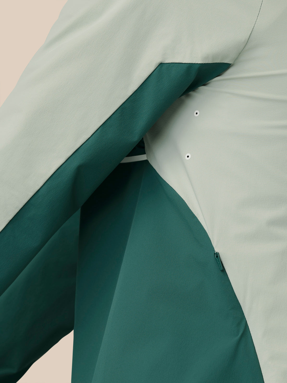 Close-up of Sage wind jacket fabric showing two-tone panels and zipper detail.