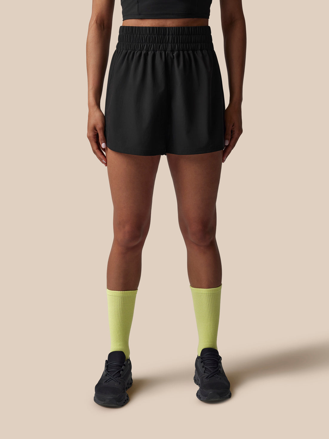 Person wearing black athletic shorts and yellow socks on a beige background