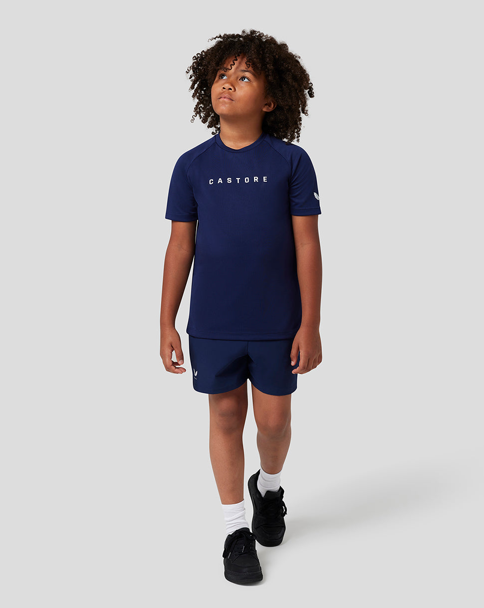 Full body shot of a child wearing navy Raglan T shirt and matching shorts with Castore branding on chest and sleeve