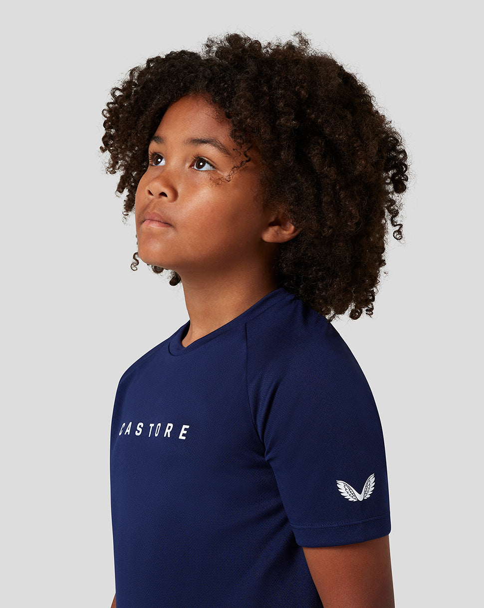 Girl in navy Castore short sleeve raglan tee shown from the side with chest branding and wing logo on sleeve