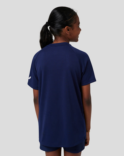 Back view of a child in navy Raglan T shirt and shorts with a small emblem on the sleeve