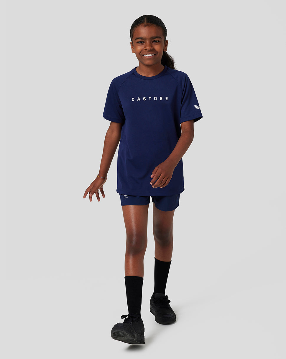 Smiling girl in navy Castore short sleeve raglan tee with matching shorts and branding on chest and sleeve