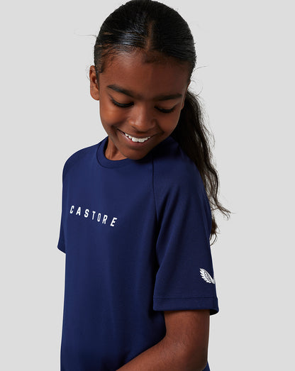 Front view of a girl in navy Junior Short Sleeve Raglan T Shirt with CASTORE branding on chest and a wing emblem on the sleeve
