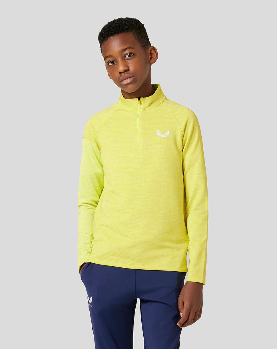 Portrait of a young boy wearing a bright yellow Citrus Junior Standard 1/4 Zip top with a neck zipper.