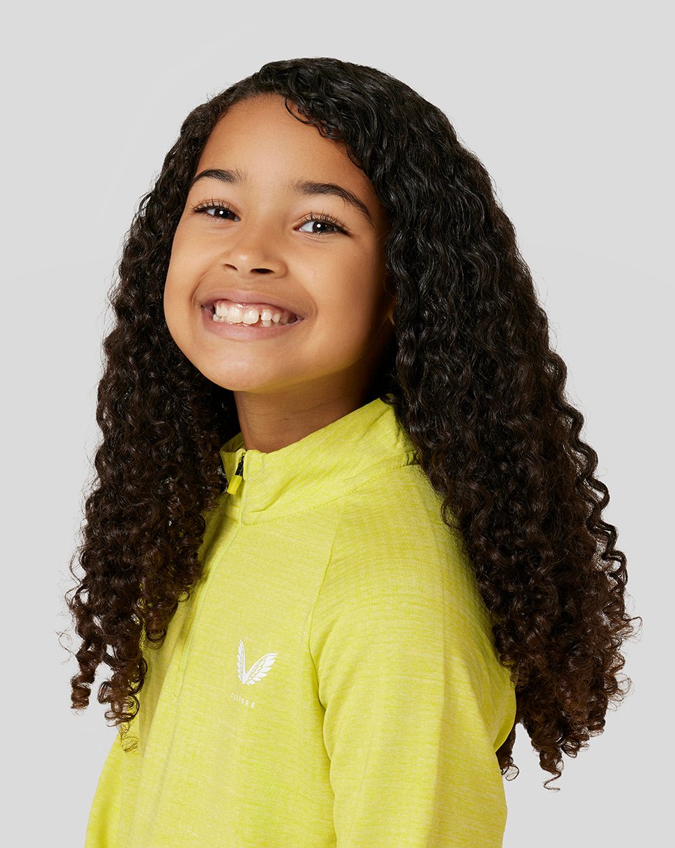 Close up of a smiling girl wearing a bright lime Citrus Junior Standard 1/4 Zip with a white emblem on the chest.