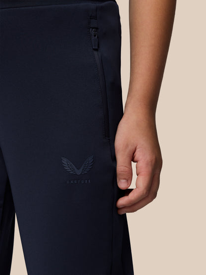 Close-up of navy Junior’s Flex Scuba Trousers showing a side zip pocket and Castore logo on the leg.