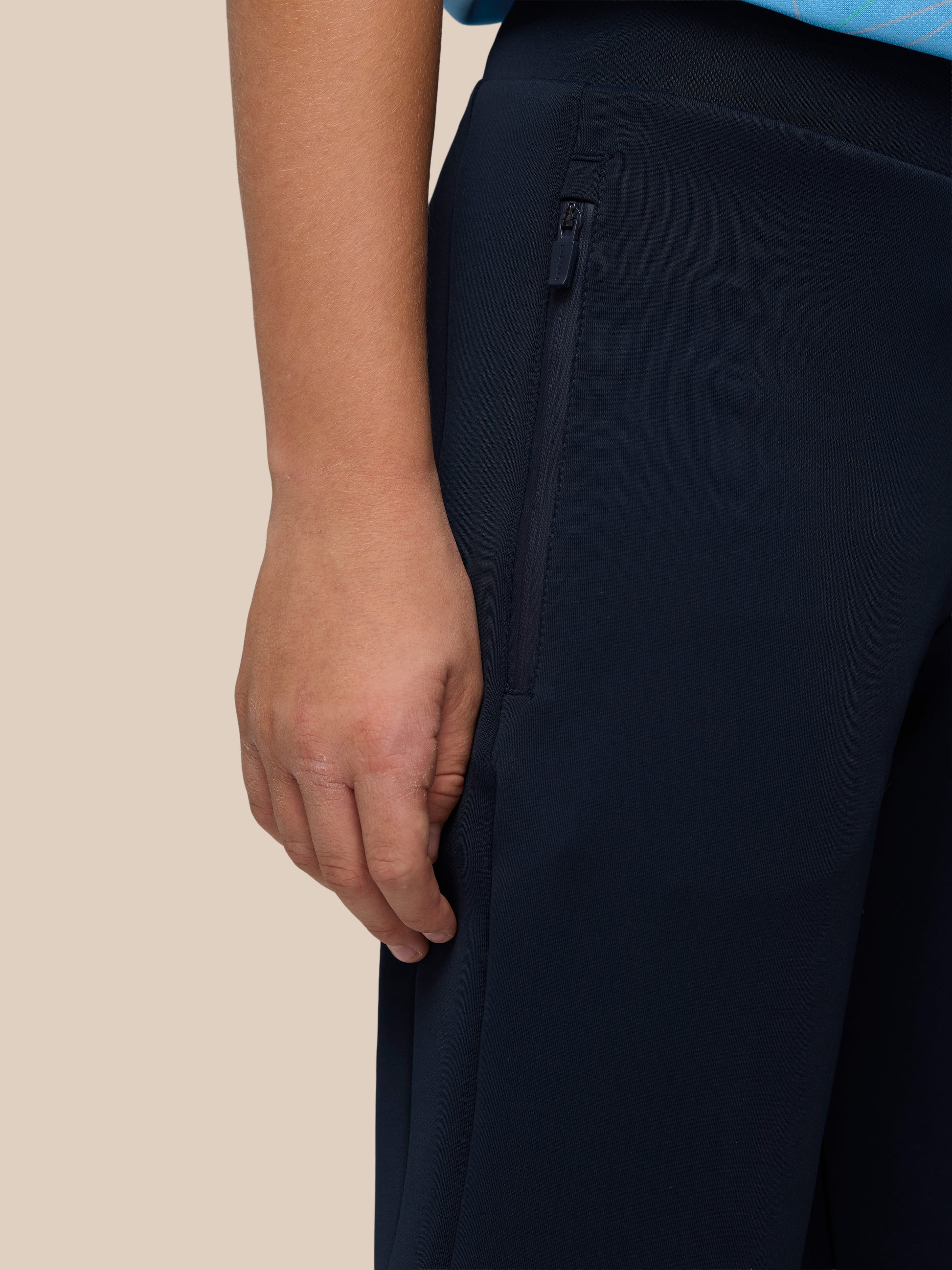 Close-up of navy Junior’s Flex Scuba Trousers showing a zippered side pocket and textured fabric.