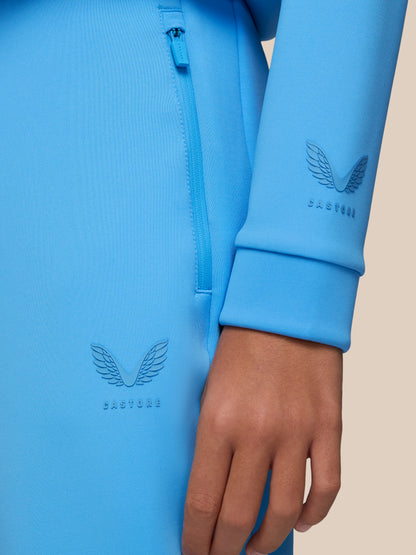 Close-up of bright blue Castore scuba fabric with a vertical zip pocket and embossed wing logo