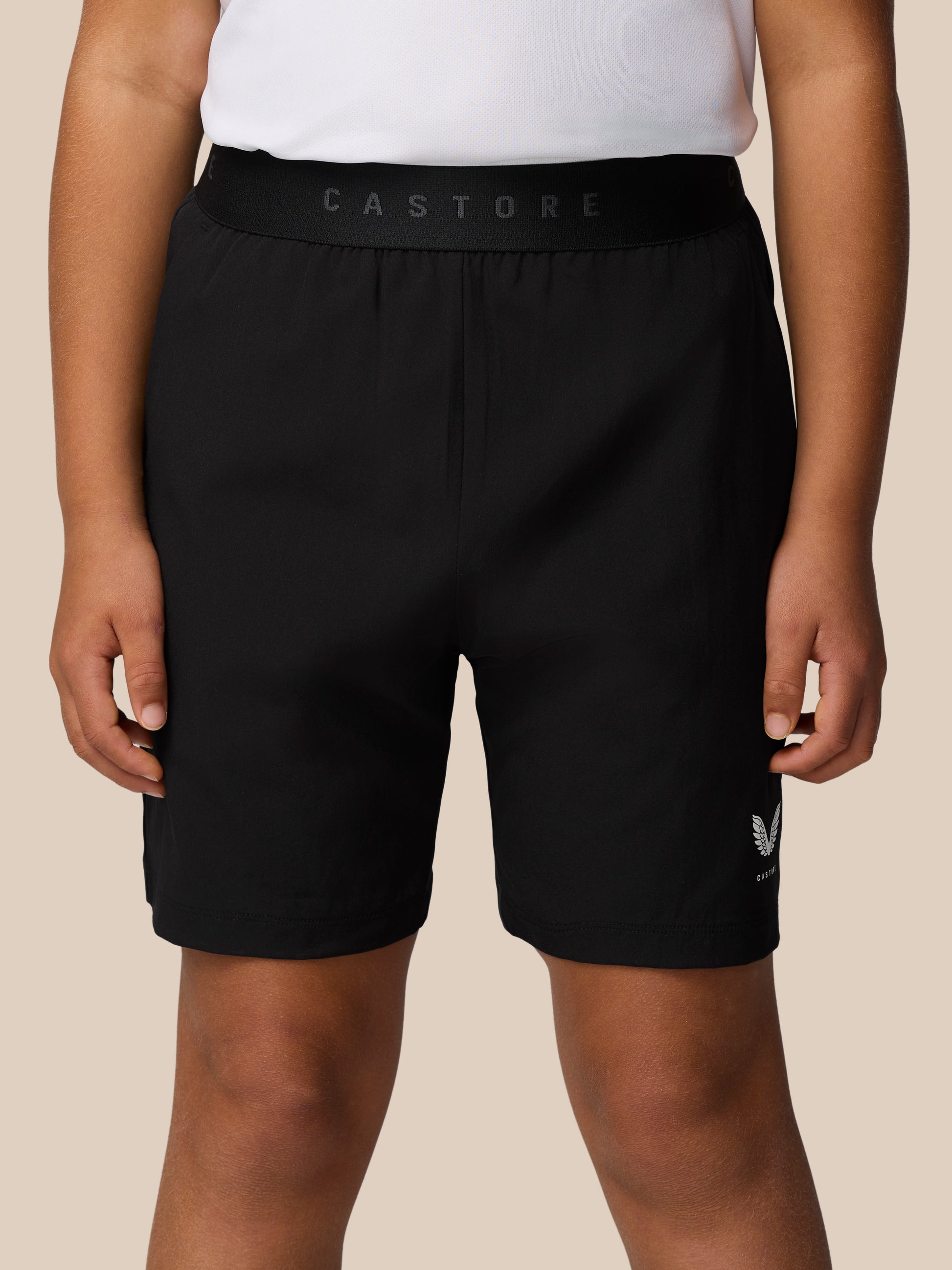 Close up of black Junior Adapt Woven Shorts with a wide elastic waistband and Castore branding on the front leg