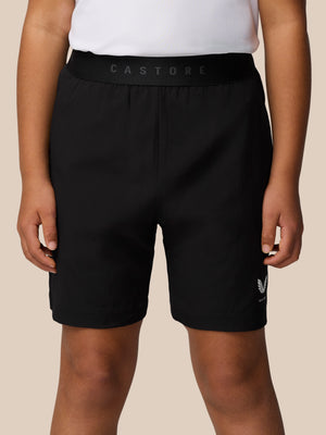 Close up of black Junior Adapt Woven Shorts with a wide elastic waistband and Castore branding on the front leg