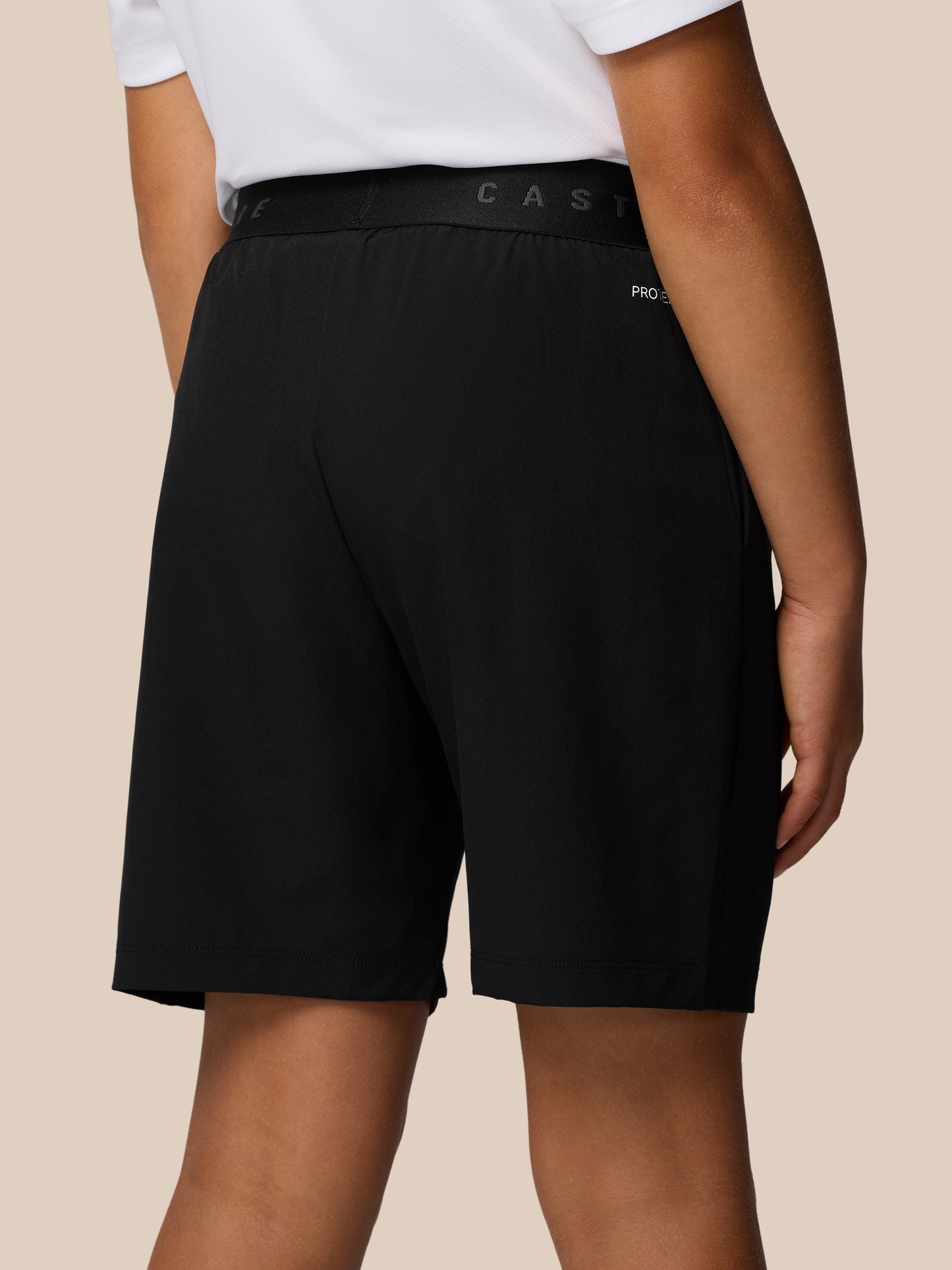 Close up of the waistband area on black Junior’s Adapt Woven Shorts showing Castore branding and ProTek detailing.