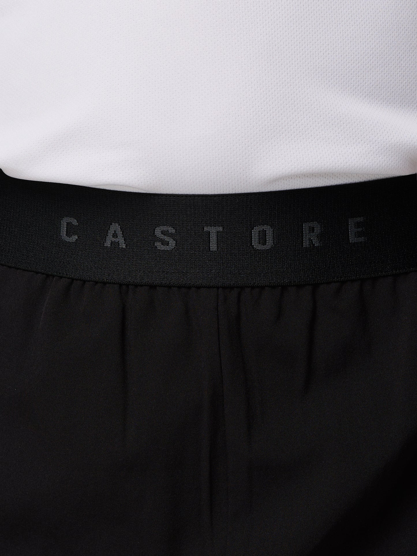Close up of a black Castore waistband on Junior's Adapt Woven Shorts with a white top visible.
