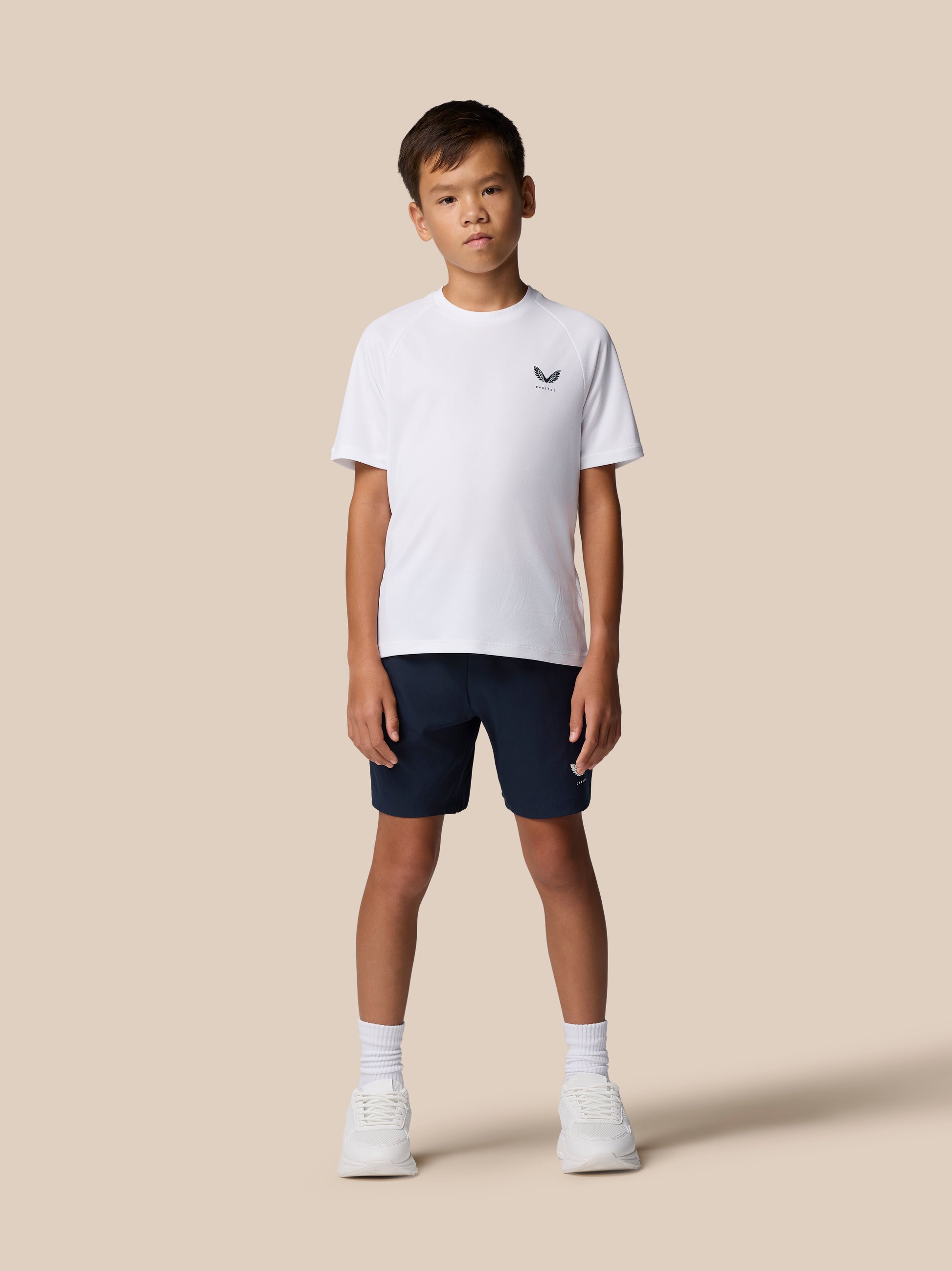Young model wearing Junior’s Adapt Woven Shorts in navy with a small logo on the left thigh.