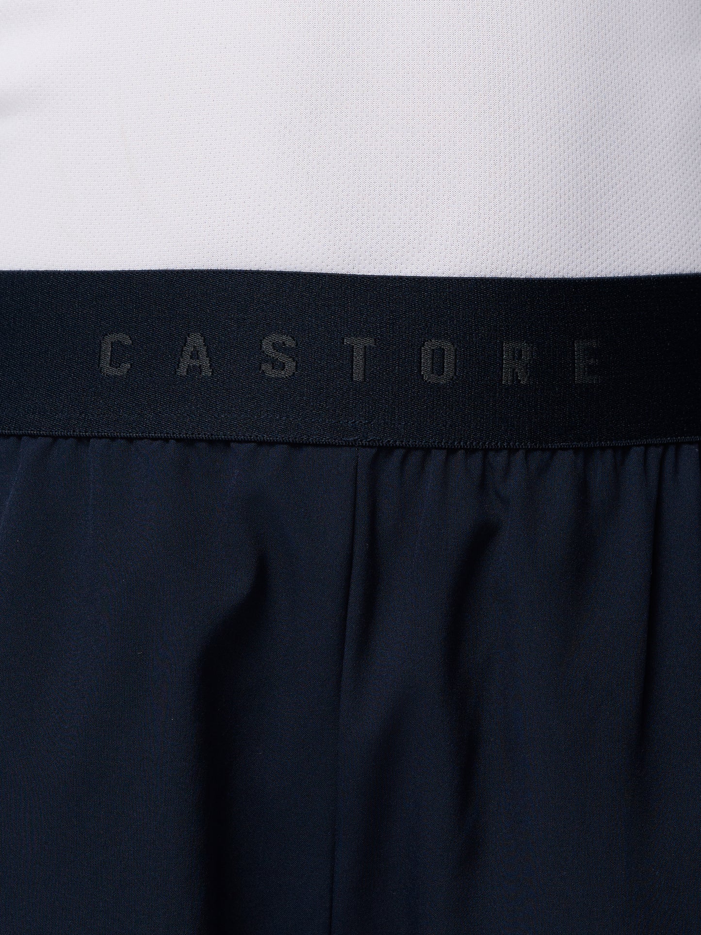 Close up of navy Junior’s Adapt Woven Shorts waistband showing a black elastic band with Castore branding.